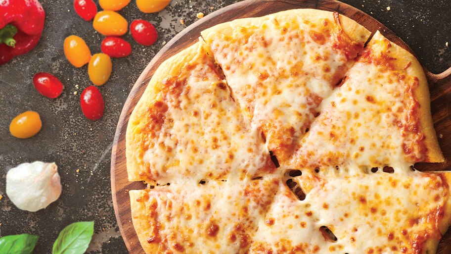 Una pizza DiGiorno en una bandeja de madera cerca de tomates cherry, un pimiento rojo y albahaca en un mostrador de granito.