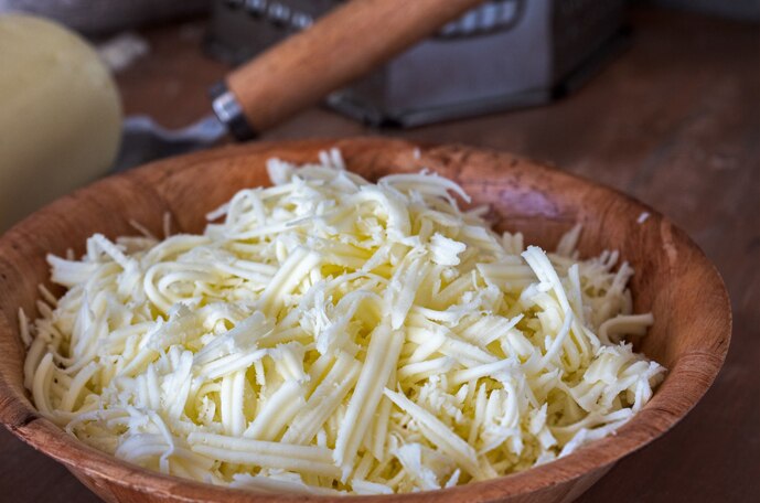 Un montoncito de queso rallado en un tazón de madera.