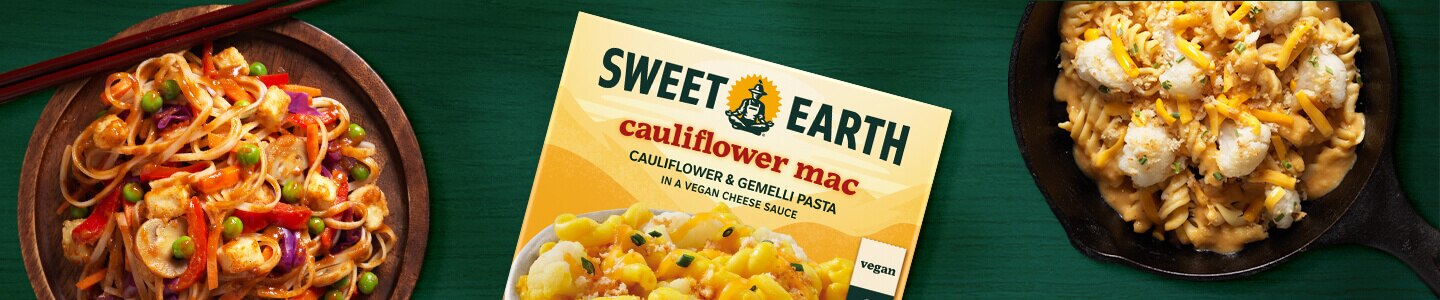 Cauliflower Mac en una sartén, envase de Cauliflower Mac y Pad Thai en un plato de madera con palillos sobre una superficie verde.
