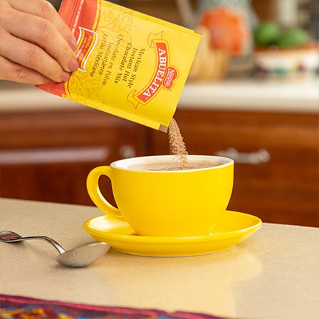 Una taza color amarillo con humeante agua caliente sobre una mesa de madera.