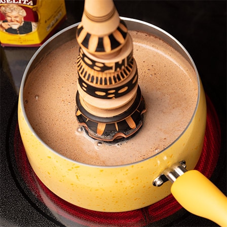 Un humeante chocolate caliente se vierte en una taza color amarillo.