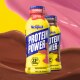Olas de leche de chocolate y fresa detrás de botellas de Protein Power de fresa y chocolate.